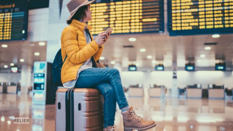 Traveler in Barcelona-El Prat Airport terminal with luggage, surrounded by modern glass architecture and natural light.